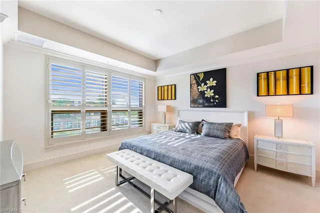 a bedroom with a bed two lamps and a large window