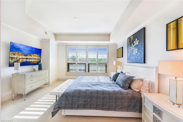 a bedroom with a large bed and a flat tv screen on dresser