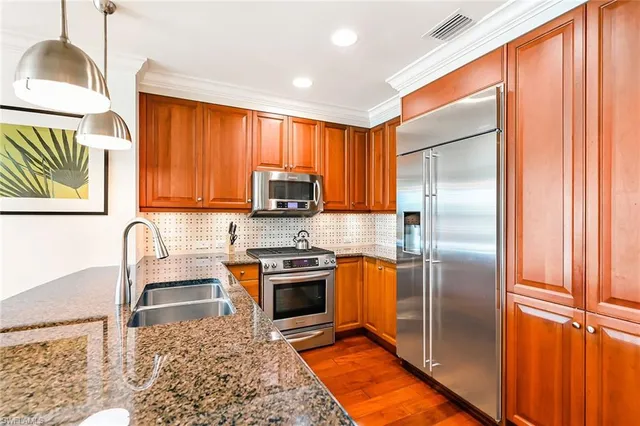a kitchen with stainless steel appliances granite countertop a refrigerator a stove top oven a sink and dishwasher