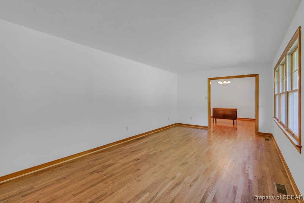 35 Powhatan Road Kilmarnock, VA 22482 - Photo 8 of 42 Empty room with a notable chandelier, baseboards, light wood finished floors, and visible vents