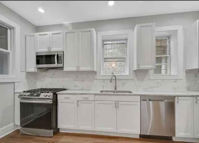 a kitchen with granite countertop white cabinets and stainless steel appliances