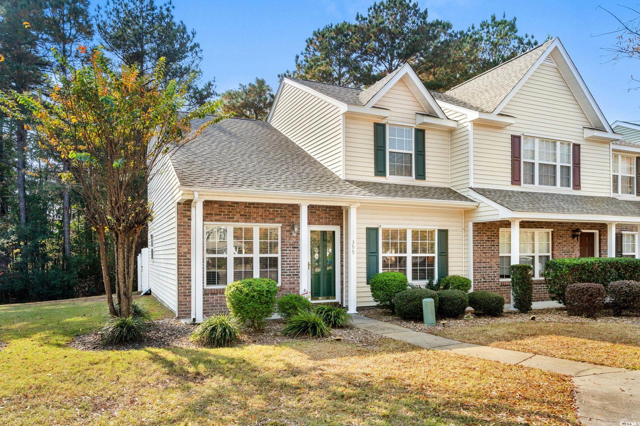 Traditional home featuring brick siding, roof with shingles, a porch, and a front lawn