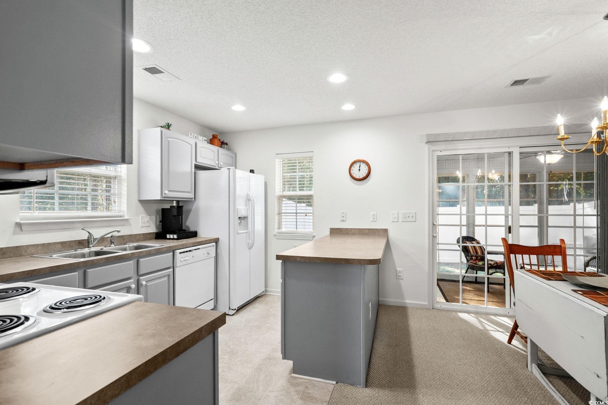 399 Seabert Road, Unit 209 Myrtle Beach, SC 29579 - Photo 11 of 40 Kitchen featuring gray cabinetry, white appliances, recessed lighting, a textured ceiling, and a peninsula