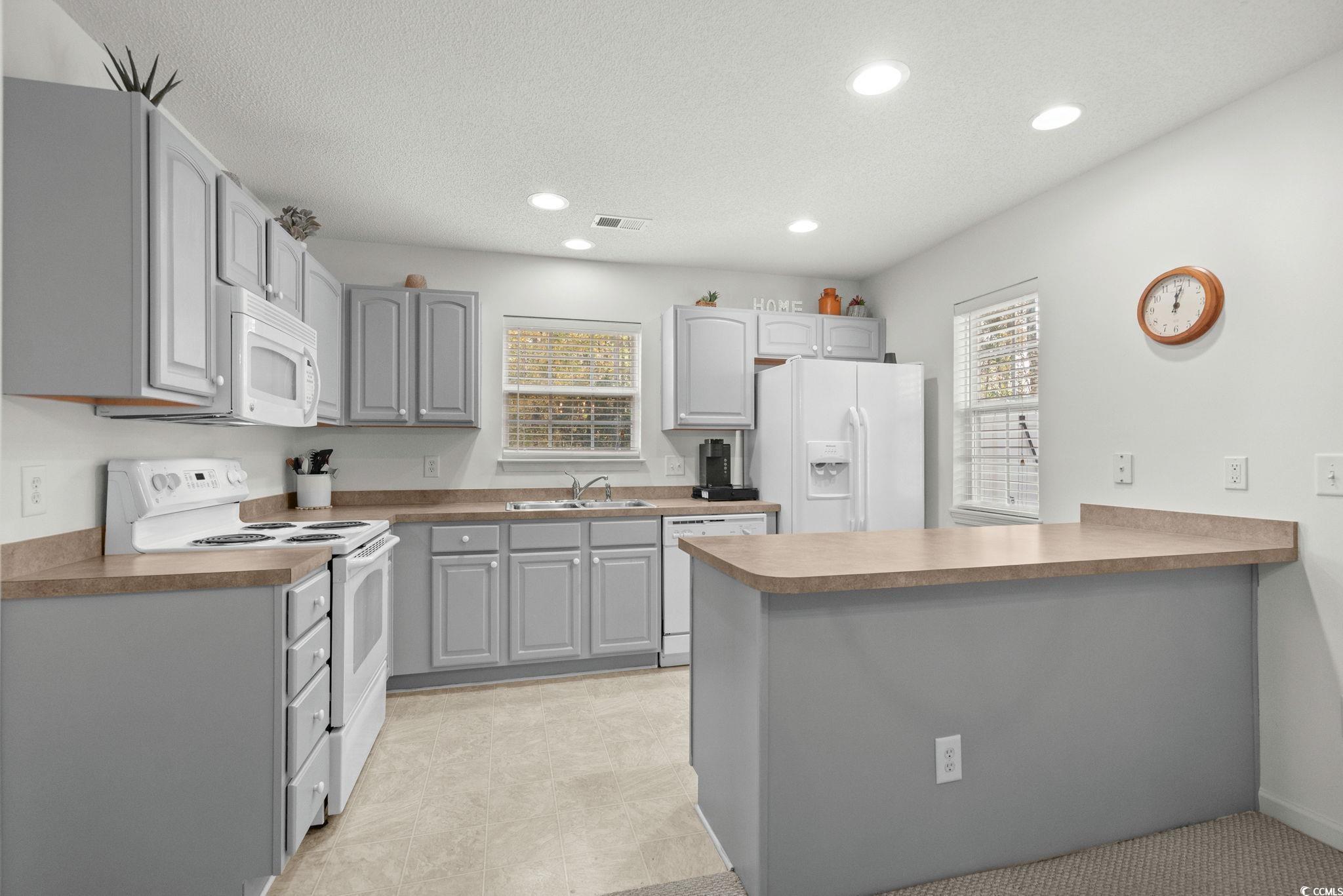 399 Seabert Road, Unit 209 Myrtle Beach, SC 29579 - Photo 14 of 40 Kitchen featuring white appliances, gray cabinetry, a peninsula, recessed lighting, and a textured ceiling