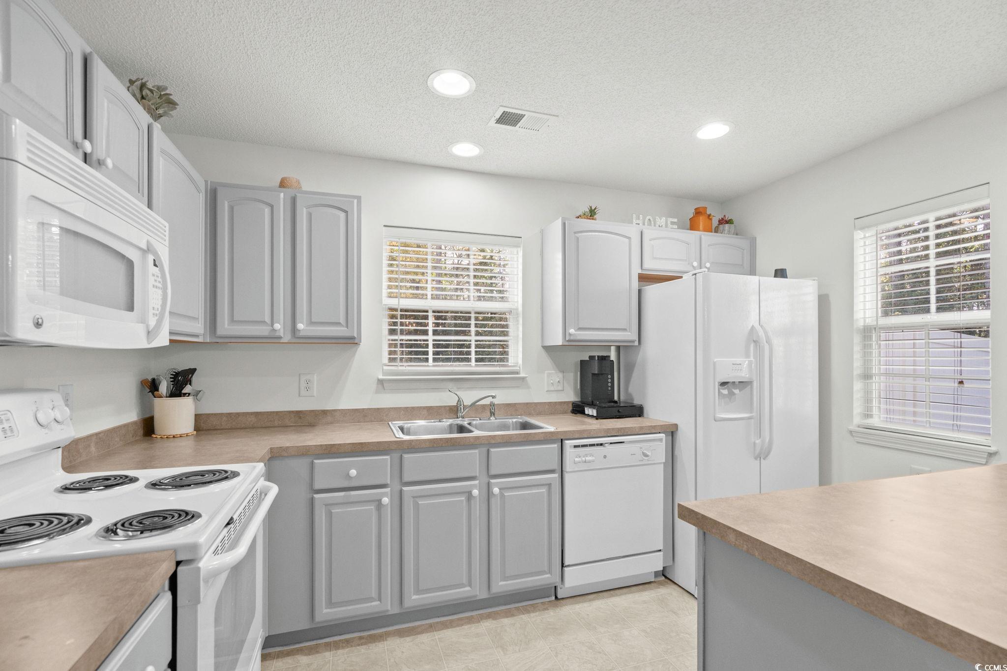 399 Seabert Road, Unit 209 Myrtle Beach, SC 29579 - Photo 15 of 40 Kitchen with white appliances, gray cabinetry, a textured ceiling, light countertops, and recessed lighting