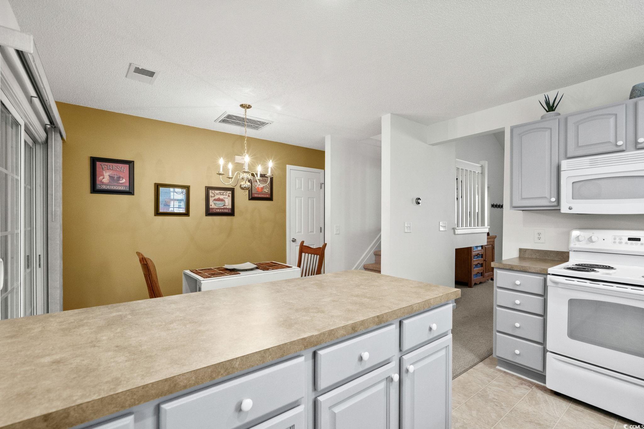 399 Seabert Road, Unit 209 Myrtle Beach, SC 29579 - Photo 18 of 40 Kitchen with white appliances, gray cabinets, decorative light fixtures, a chandelier, and a textured ceiling