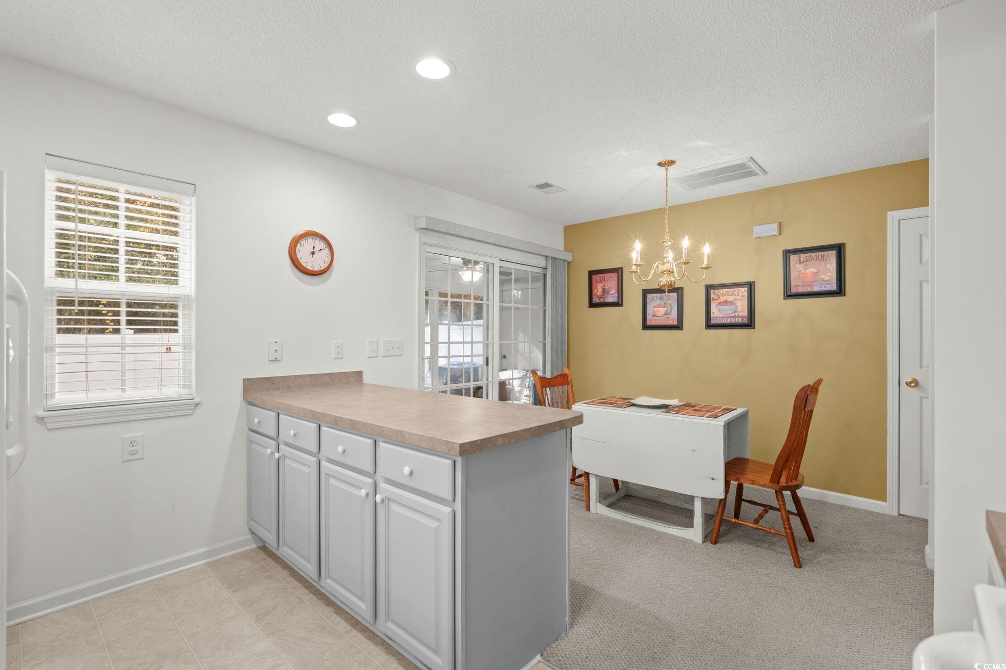 399 Seabert Road, Unit 209 Myrtle Beach, SC 29579 - Photo 19 of 40 Kitchen featuring a peninsula, decorative light fixtures, a chandelier, healthy amount of natural light, and a textured ceiling