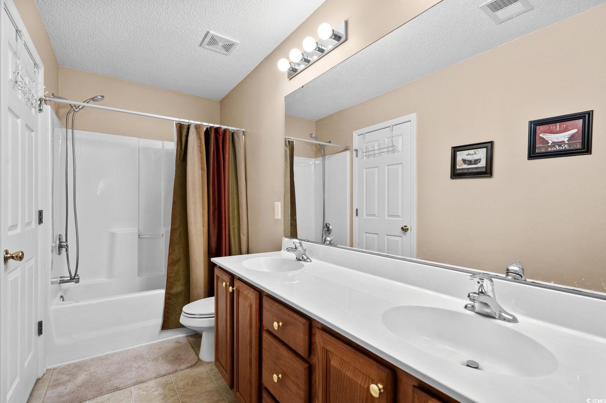 399 Seabert Road, Unit 209 Myrtle Beach, SC 29579 - Photo 28 of 40 Full bath featuring a textured ceiling, shower / tub combo, double vanity, and light tile patterned floors