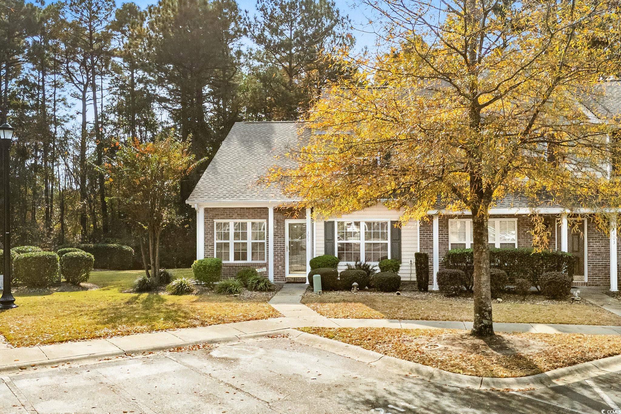 399 Seabert Road, Unit 209 Myrtle Beach, SC 29579 - Photo 3 of 40 View of property hidden behind natural elements with roof with shingles, a front yard, and brick siding