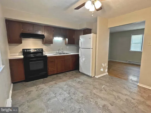 a kitchen with granite countertop a refrigerator and a stove top oven