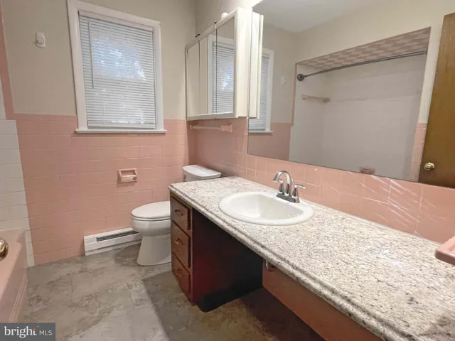 a bathroom with a granite countertop sink a toilet and a mirror