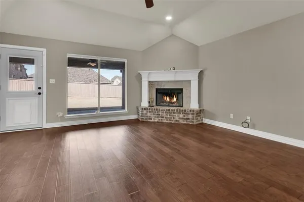 an empty room with wooden floor fireplace and windows