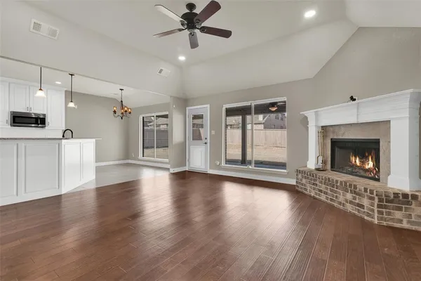 a view of an empty room with wooden floor fireplace and a window