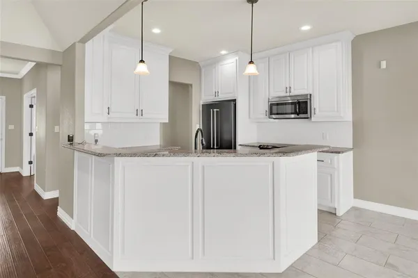 a kitchen with kitchen island granite countertop white cabinets and refrigerator