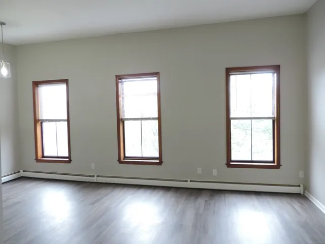a view of a hallway with wooden floor and a bathroom