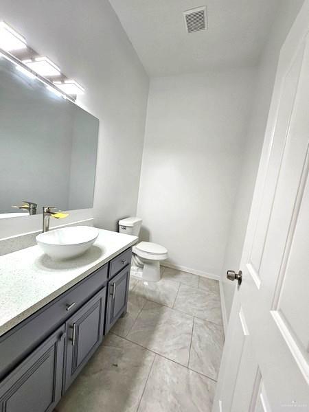 6720 North 4th Street McAllen, TX 78504 - Photo 7 of 25 a bathroom with a granite countertop sink a toilet and a mirror
