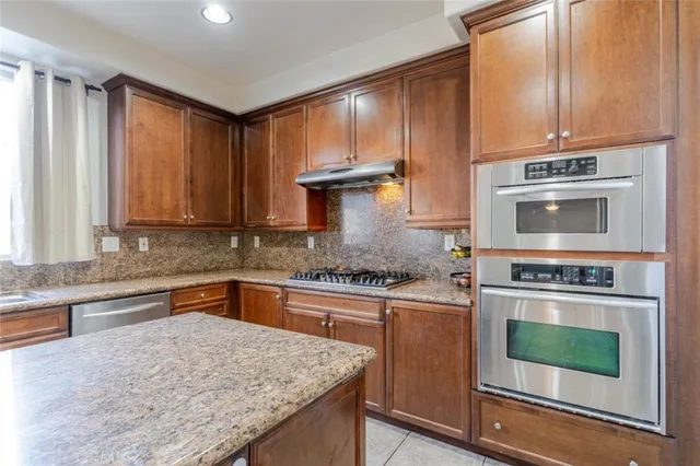 a kitchen with granite countertop wooden cabinets stainless steel appliances and a counter space