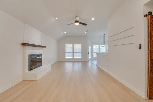an empty room with wooden floor fireplace and windows