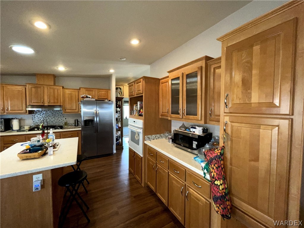 10551 East Blake Ranch Road Kingman, AZ 86401 - Photo 3 of 50 a kitchen with stainless steel appliances granite countertop a refrigerator a stove and a sink with wooden floor