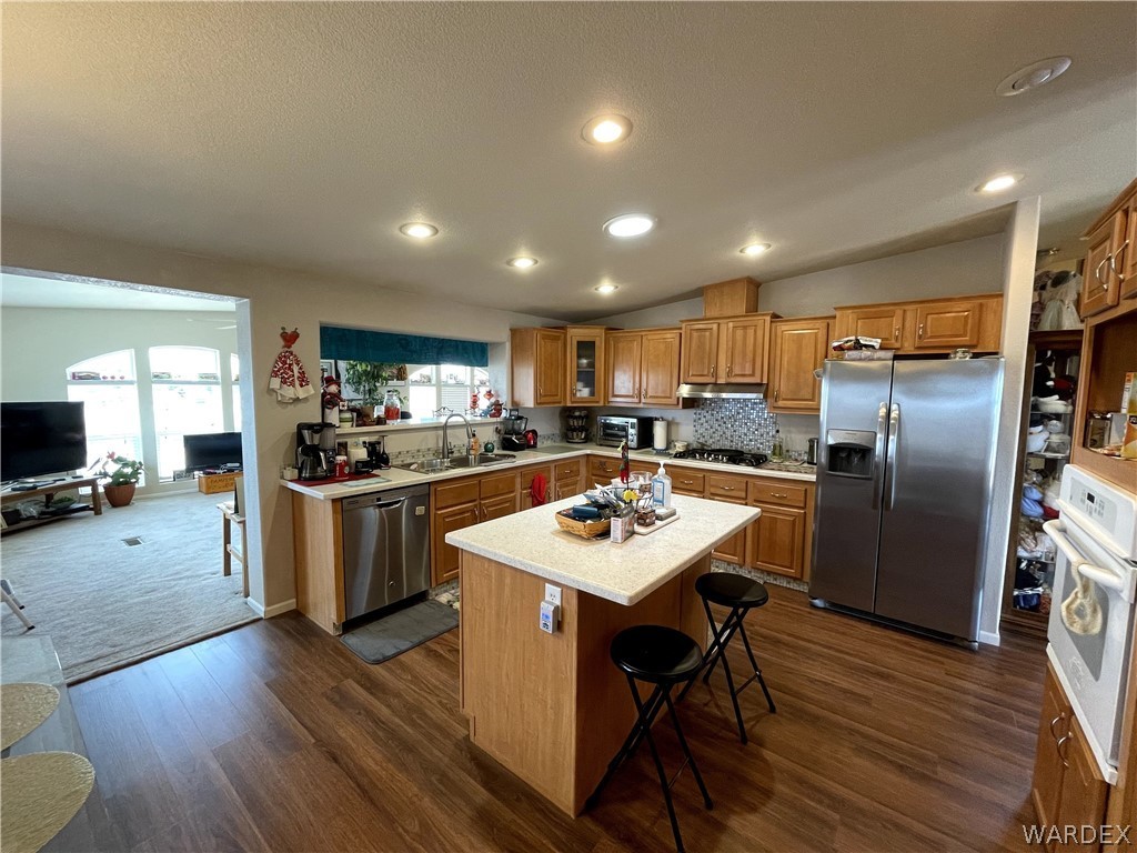 10551 East Blake Ranch Road Kingman, AZ 86401 - Photo 4 of 50 a kitchen with stainless steel appliances kitchen island granite countertop a refrigerator a sink a stove a dining table and chairs with wooden floor
