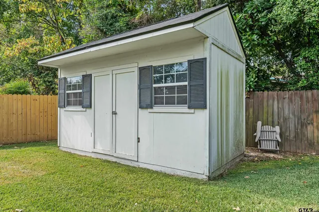 a view of backyard with a barn and a large tree