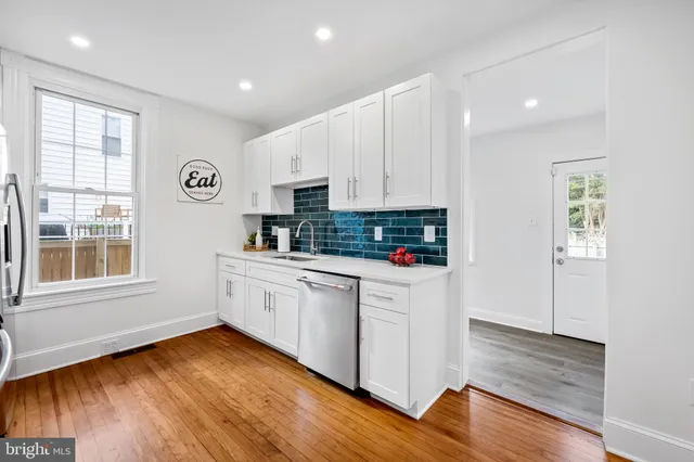 a kitchen with wooden floors and white cabinets