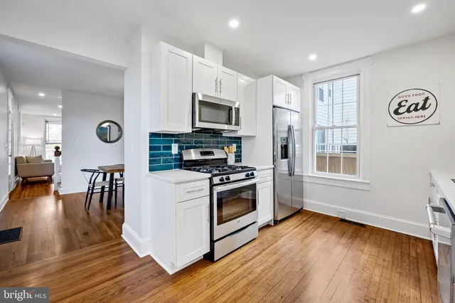 a kitchen with stainless steel appliances granite countertop a stove a sink dishwasher and a microwave oven with wooden floor