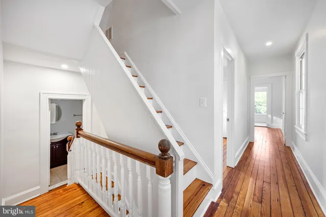 a view of a hallway with wooden floor and staircase