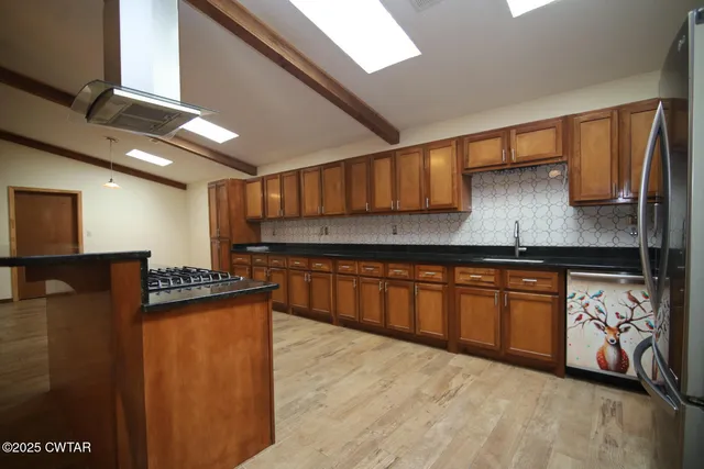 a kitchen with stainless steel appliances granite countertop a stove a sink and a refrigerator