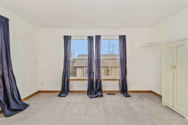 an empty room with closet and windows