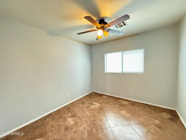 an empty room with a ceiling fan and carpet