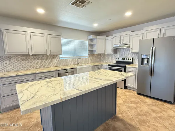a large kitchen with kitchen island granite countertop a sink counter space cabinets and stainless steel appliances
