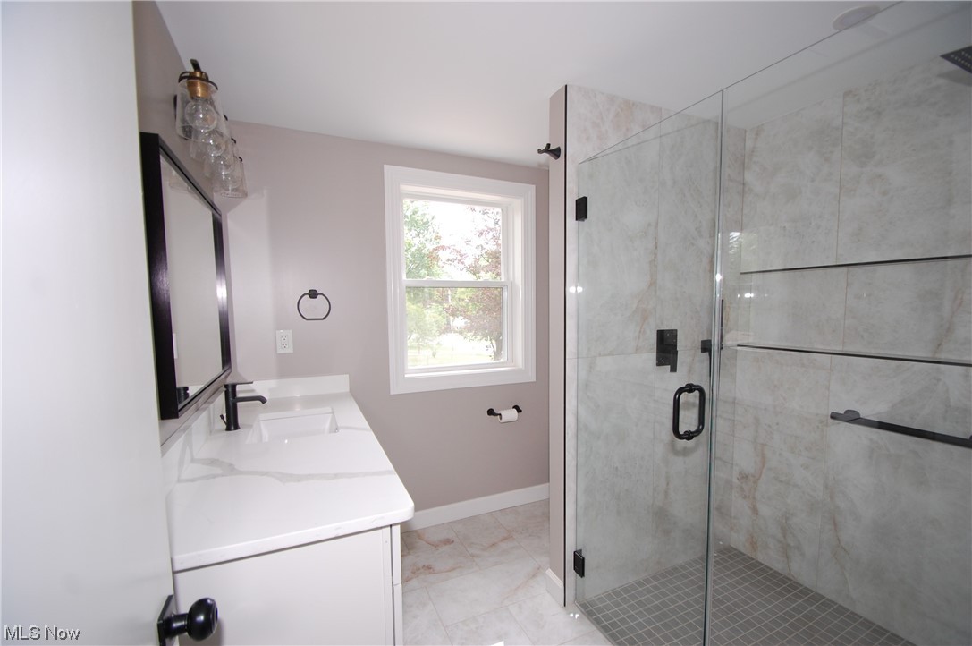 408 Ewing Road Youngstown, OH 44512 - Photo 23 of 31 Bathroom featuring a shower with shower door, double sink vanity, mirror, and light tile floors