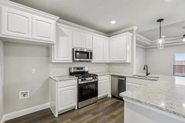 a kitchen with stainless steel appliances granite countertop a sink a stove and a wooden floor