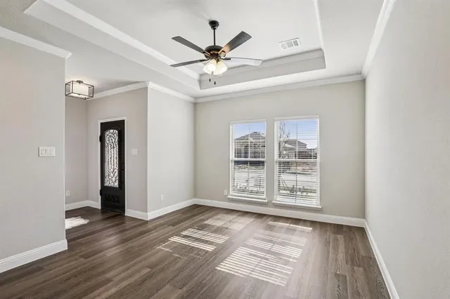 an empty room with wooden floor a ceiling fan and windows
