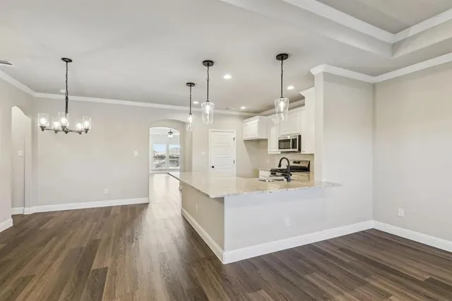 a large kitchen with cabinets wooden floor and a chandelier