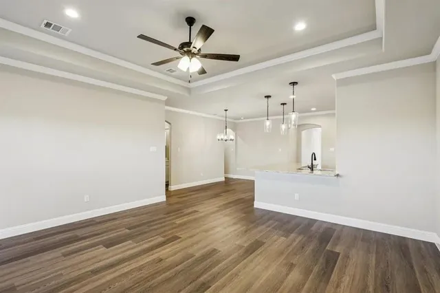 a view of a livingroom with a ceiling fan wooden floor and a ceiling fan