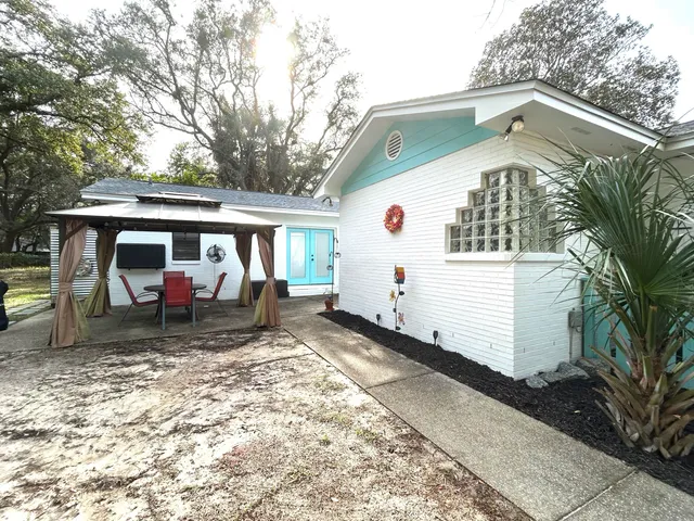 a view of a house with a yard and lawn chairs under an umbrella
