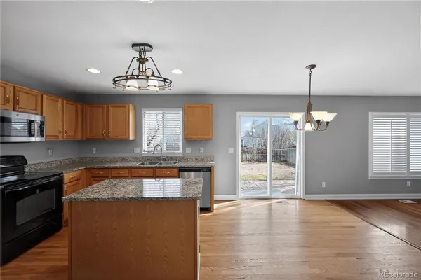 a large kitchen with granite countertop a stove and a wooden floors