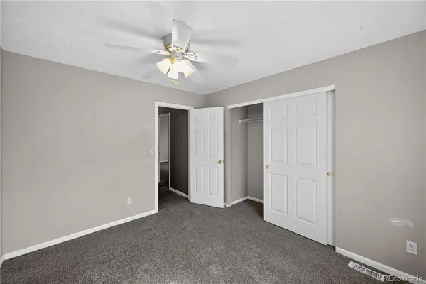 a view of an empty room with a chandelier fan