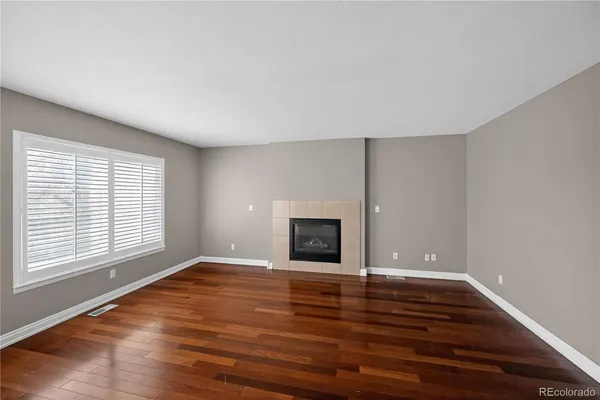 a view of empty room with wooden floor and fireplace