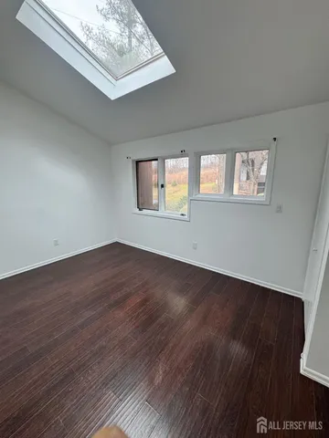 a view of an empty room with wooden floor and window