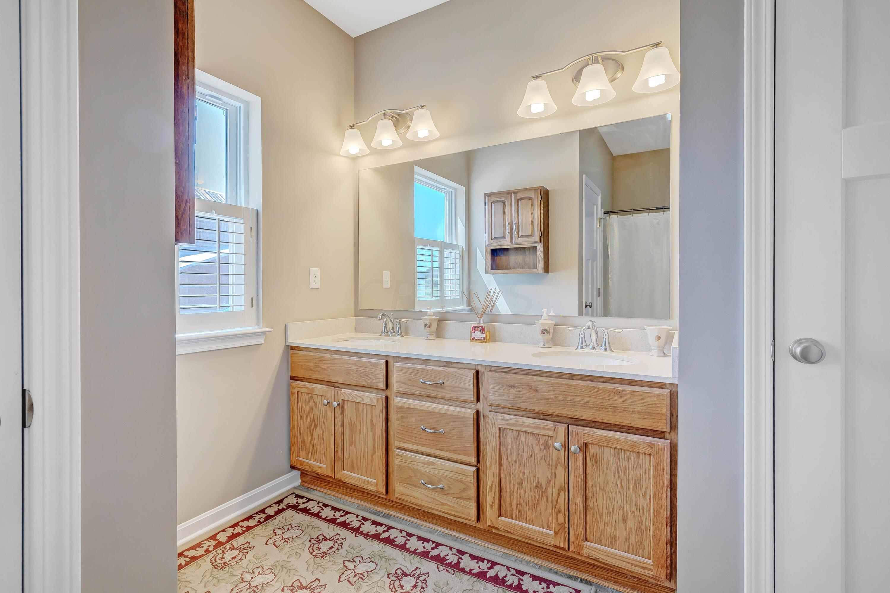 16347 Murphy Road Sunbury, OH 43074 - Photo 25 of 74 • Neutral vinyl flooring • Tan painted walls • Enclosed vanity with double bowl cultured marble sinktop • Linen closet • (2) 3 bulb wall lights • Shower stall with seat • Lighted ceiling exhaust • Wall cabinet • Window shutters
