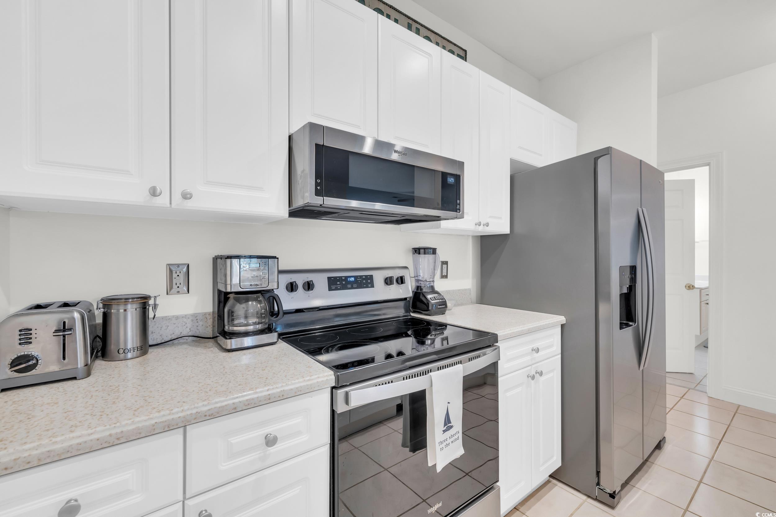 141 Twelve Oaks Drive, Unit 5 Pawleys Island, SC 29585 - Photo 8 of 37 Kitchen with stainless steel appliances, white cabinetry, light tile patterned floors, and light stone counters