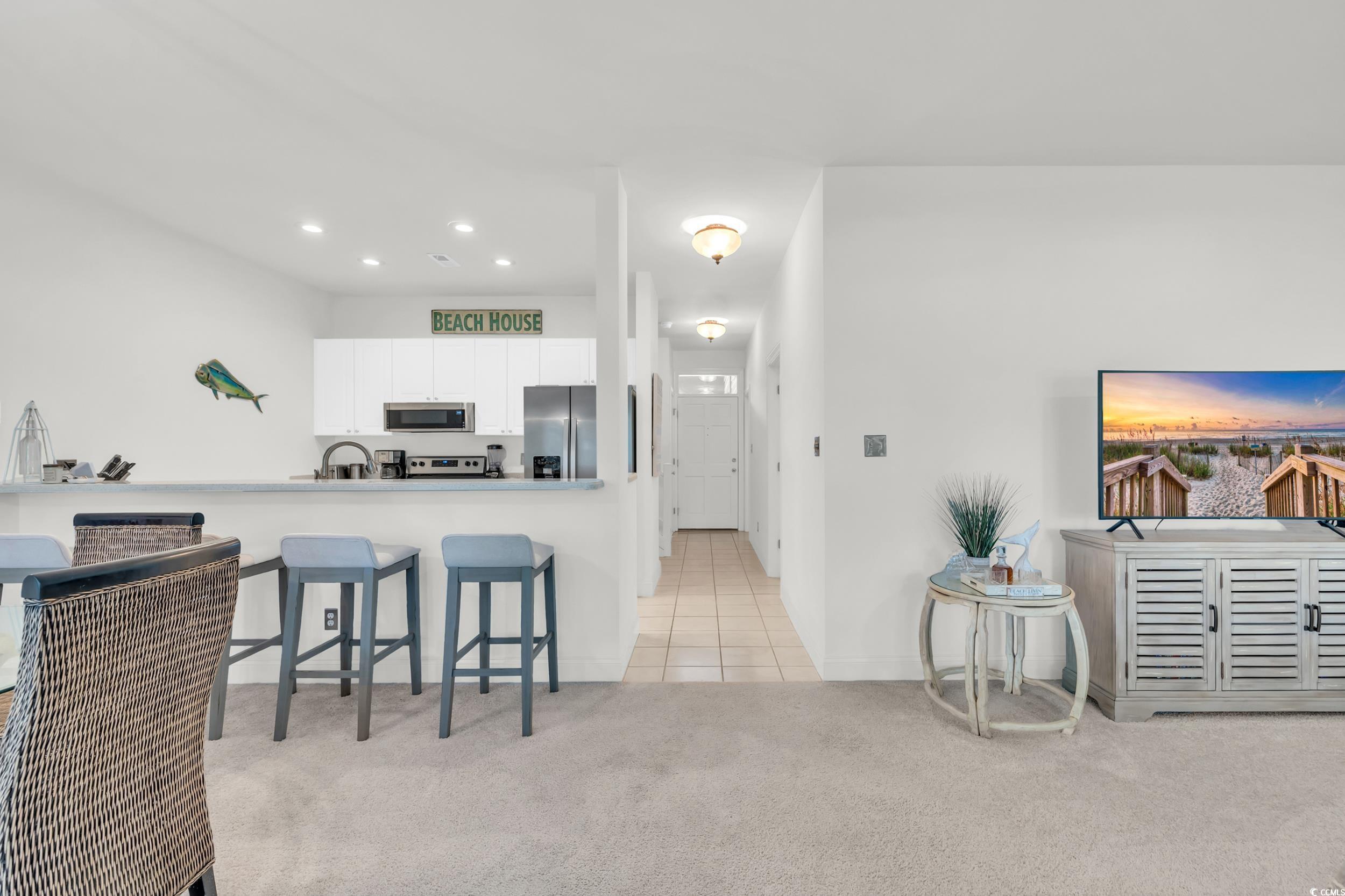 141 Twelve Oaks Drive, Unit 5 Pawleys Island, SC 29585 - Photo 10 of 37 Kitchen with a kitchen bar, white cabinets, light carpet, a peninsula, and light tile patterned floors
