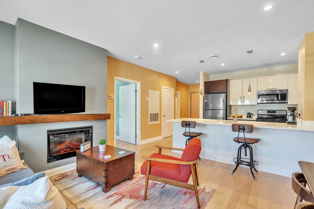 1 Brook Road, Unit 215 Quincy, MA 02169 - Photo 3 of 24 a living room with furniture a flat screen tv and a fireplace