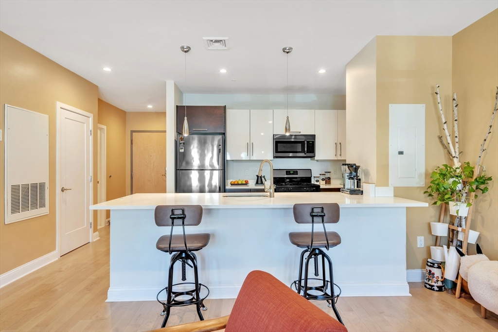 1 Brook Road, Unit 215 Quincy, MA 02169 - Photo 7 of 24 a kitchen with stainless steel appliances a dining table chairs refrigerator and sink