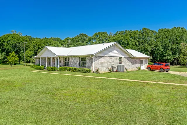 a front view of house with outdoor space and trees in the background