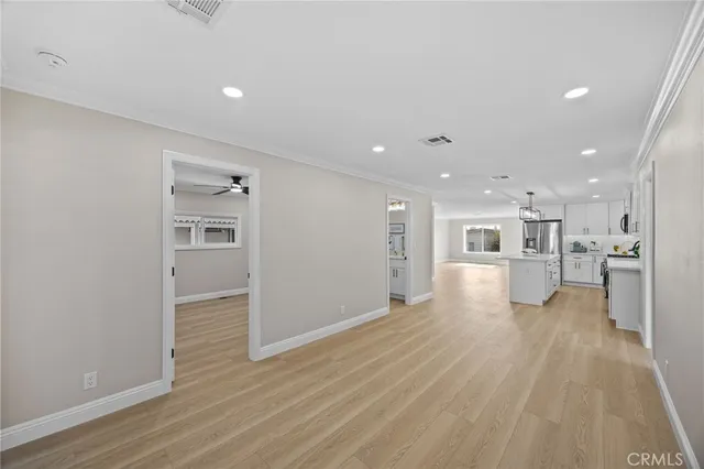 a view of a big room with wooden floor and a kitchen