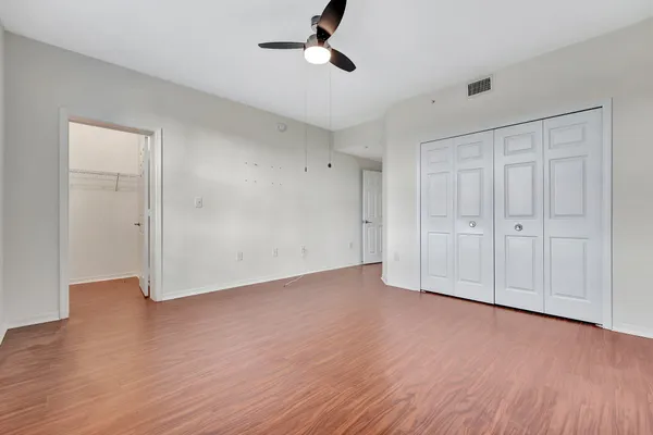 an empty room with wooden floor cabinet and windows